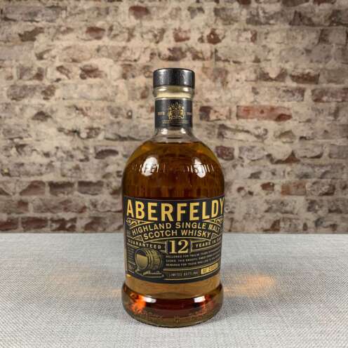 Produktbild Aberfeldy 12 Jahre Alt Attribut: Aberfeldy 12 Jahre Single Malt kaufen bei Belle Booze Whiskyglas mit goldenem Farbton und Holzunterlage Alt Attribut: Aberfeldy 12 Jahre Single Malt Geschmack Honig und Vanille Flasche Aberfeldy 12 vor schottischer Landschaft Alt Attribut: Aberfeldy 12 Jahre Highland Single Malt aus Aberfeldy, Pitilie Burn Wasserquelle