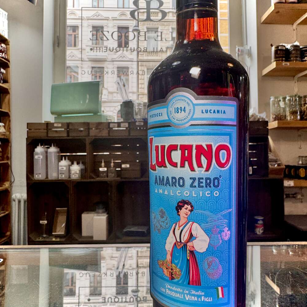 Produktbild Lucano Amaro Zero Alt‑Attribut: Lucano Amaro Zero alkoholfrei kaufen bei Belle Booze Not-Alcoholic Lucano Spritz Alt‑Attribut: Lucano Amaro Zero Spritz alkoholfrei mit Orangenscheibe Flasche vor Zitrusbäumen Alt‑Attribut: Lucano Amaro Zero – mediteraner alkoholfreier Aperitif