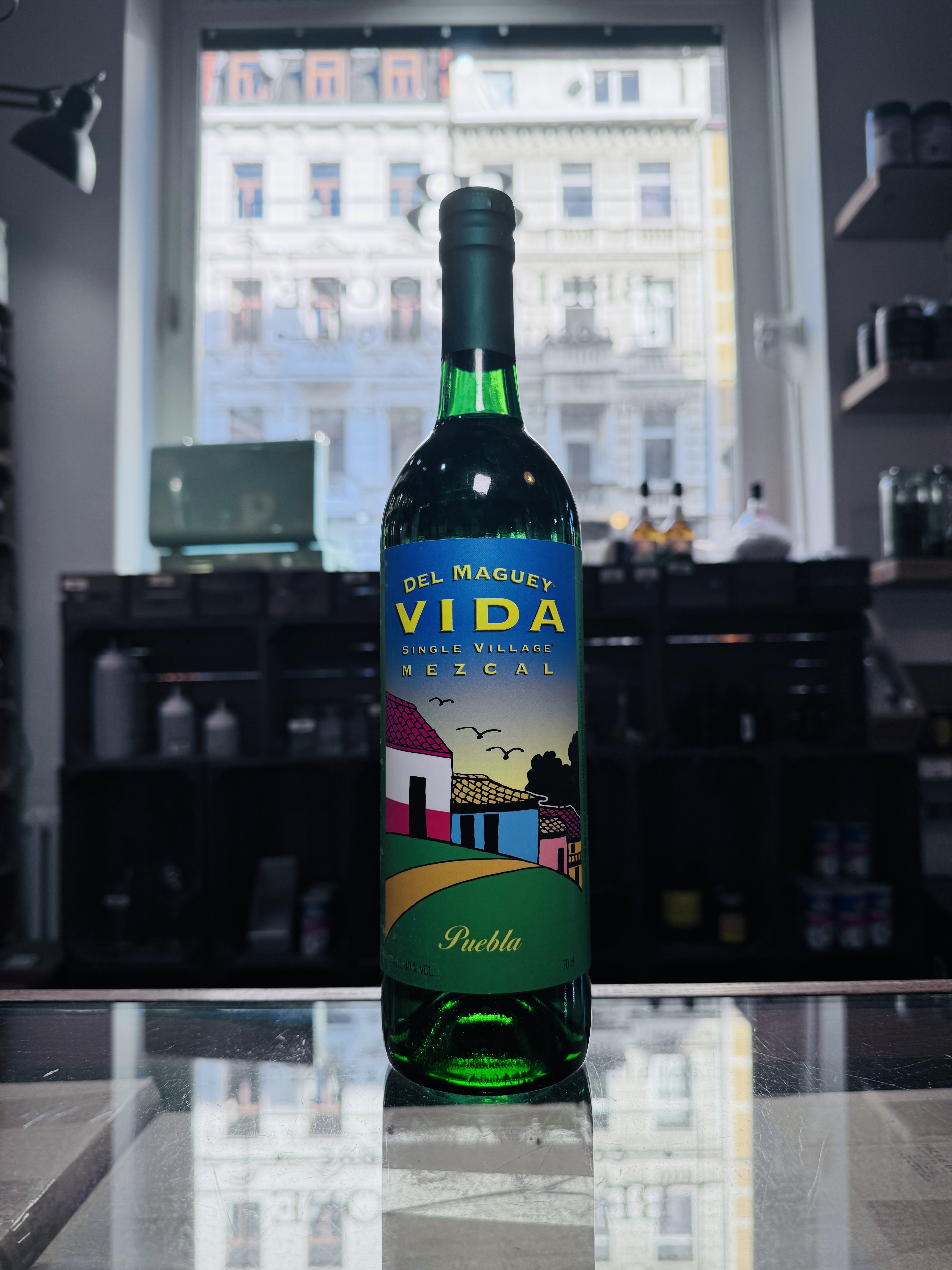 Produktbild Mezcal Vida Puebla Alt Attribut Mezcal Vida Puebla kaufen bei Belle Booze Mezcal Glas mit Rauch und Limette Alt Attribut Mezcal Vida Puebla rauchige Agave im Glas Flasche vor Agavenfeld Kulisse Alt Attribut Mezcal Vida Puebla aus Puebla Mexiko